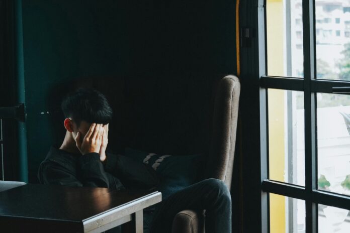 a person sitting in an office with their hands over their face
