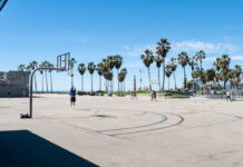 Outdoor basketball court with palm trees and players at Venice Beach, California